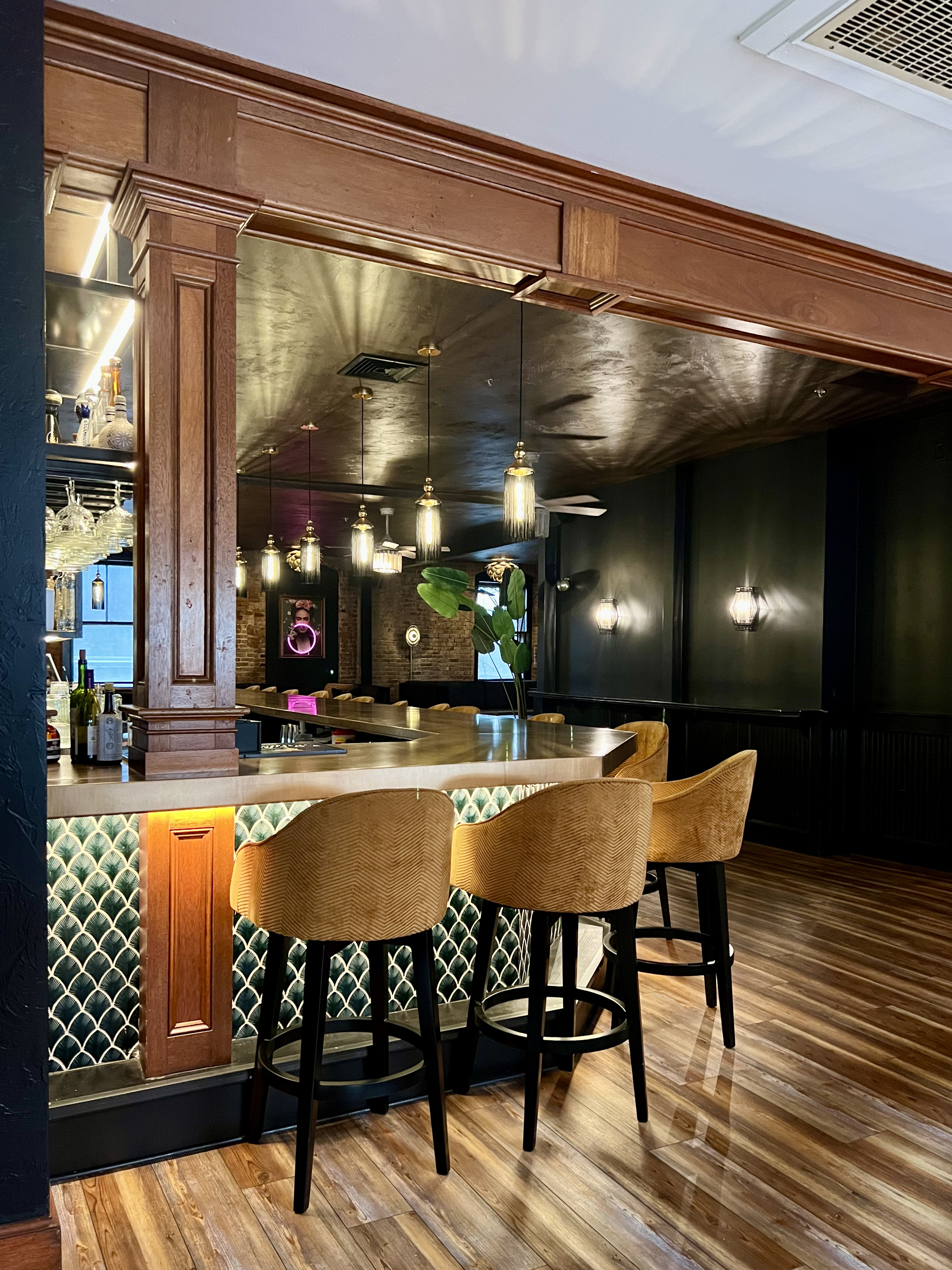 Bar with patterned green tile cladding, warm lighting and upholstered seating