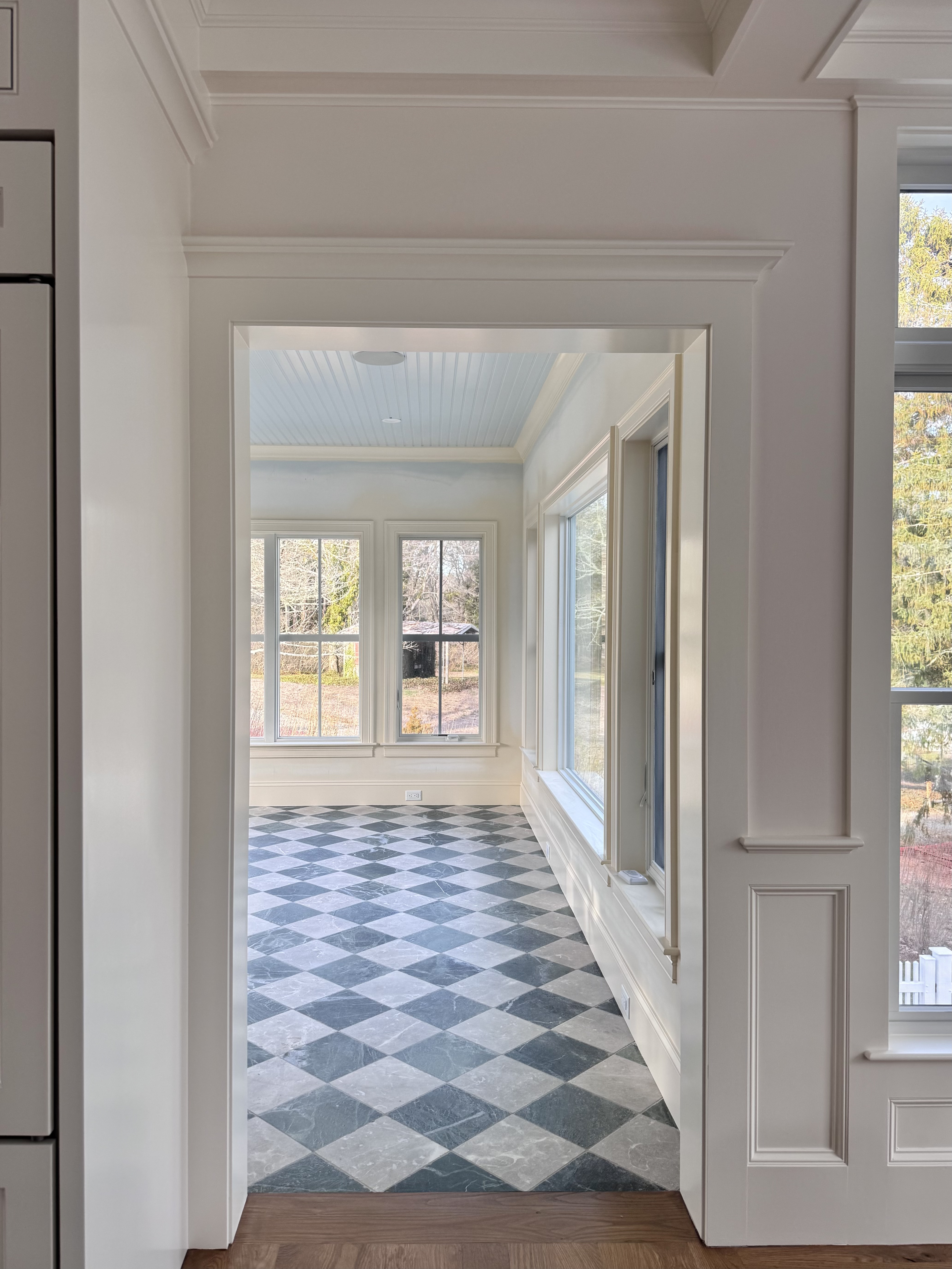 Diagonal checkerboard tile floor framed by a doorway and tall windows