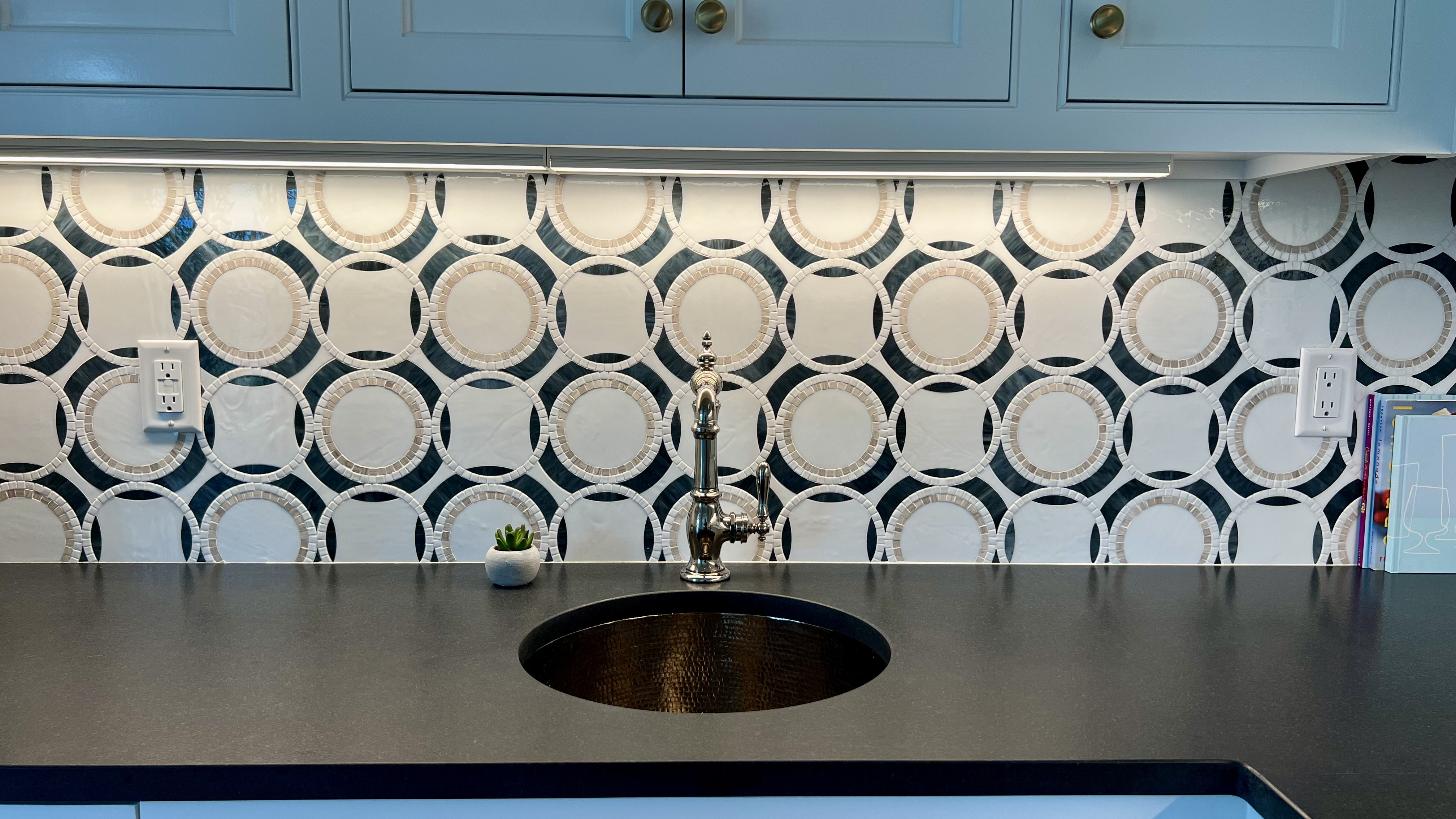 Circular mosaic tile backsplash behind a kitchen sink
